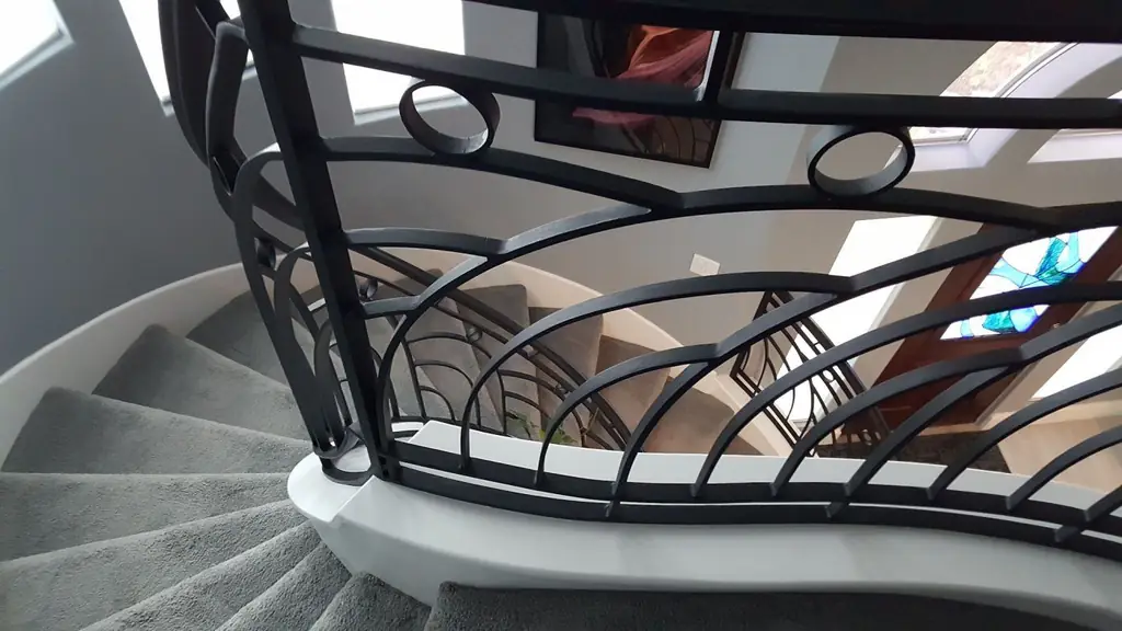 Finished custom iron handrail detail on a curved staircase built by Envision Design Build