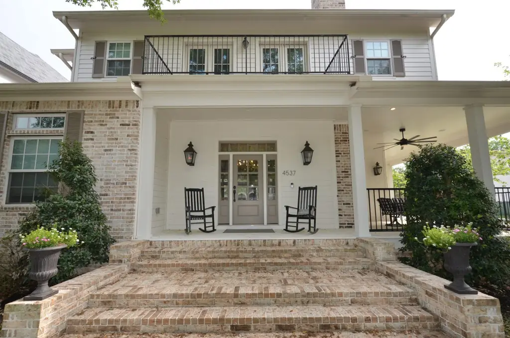 A white clapboard and brick front porch with rocking chairs, on a home designed and built by Envision Design Build