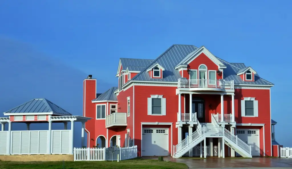 A coral Galveston beach house on piers with a silver standing seam roof, designed and built by Envision Design Build