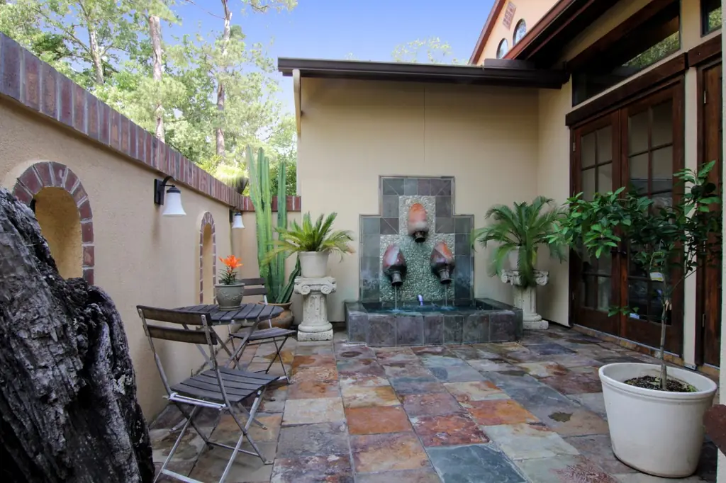 An enclosed Spanish style courtyard with a tiled wall fountain and slate paving on a custom home