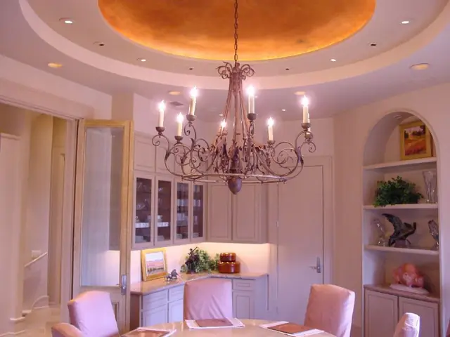 A gilt domed ceiling with an iron chandelier in a dining room