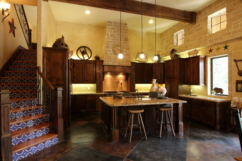A rustic Spanish-style kitchen with a stone hood and hand-painted tile stair risers, an Envision Design Build project