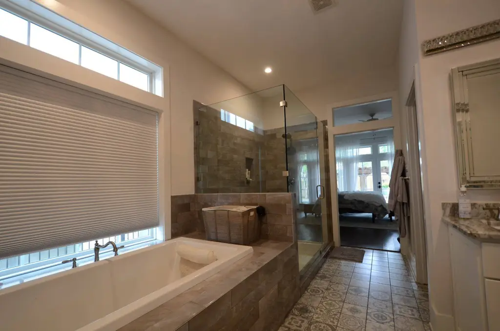 A primary bathroom with a soaking tub and glass shower in a custom home built by Envision Design Build