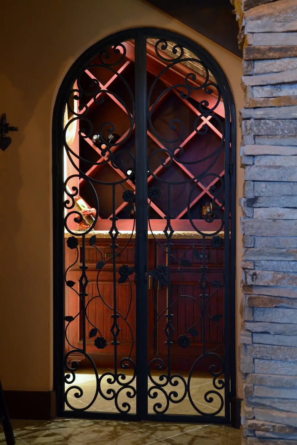 An arched wrought iron gate leading to a cedar wine room, an Envision Design Build project
