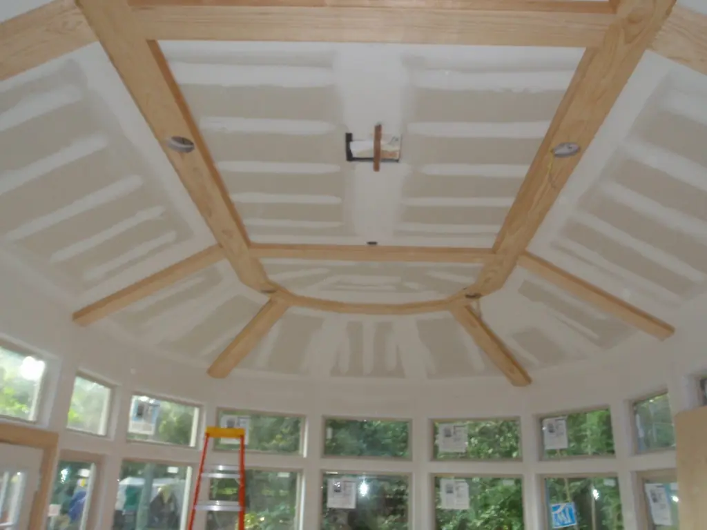 A vaulted sunroom mid-construction, exposed beams and framing visible
